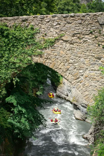 People going underneath bridge on rafts